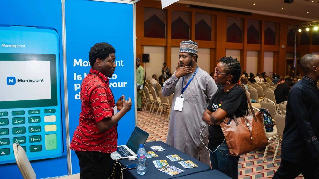 A Moniepoint Inc. representative speaks with attendees at a fintech event, as the company expands through its stake in Sumac Microfinance Bank.