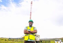 A Safaricom engineer stands beside a Cell on Wheels mobile tower deployed to extend network coverage along the Safari Rally route.