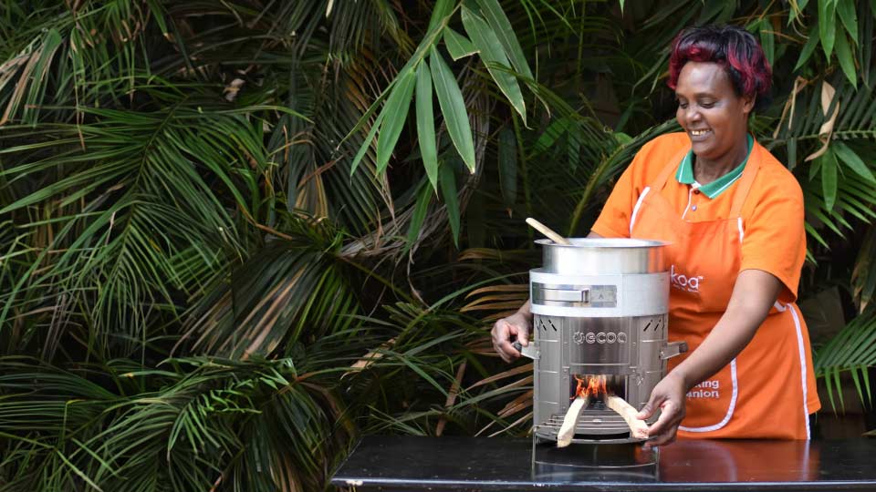 A woman demonstrates an eco-friendly cookstove in Kenya, highlighting the shift toward cleaner, more efficient household cooking solutions.
