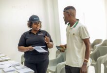 Watu Kenya Coast Regional Manager Mehetabel Mwashighadi hands over a motorcycle logbook to a customer during an asset-financing engagement in Malindi.