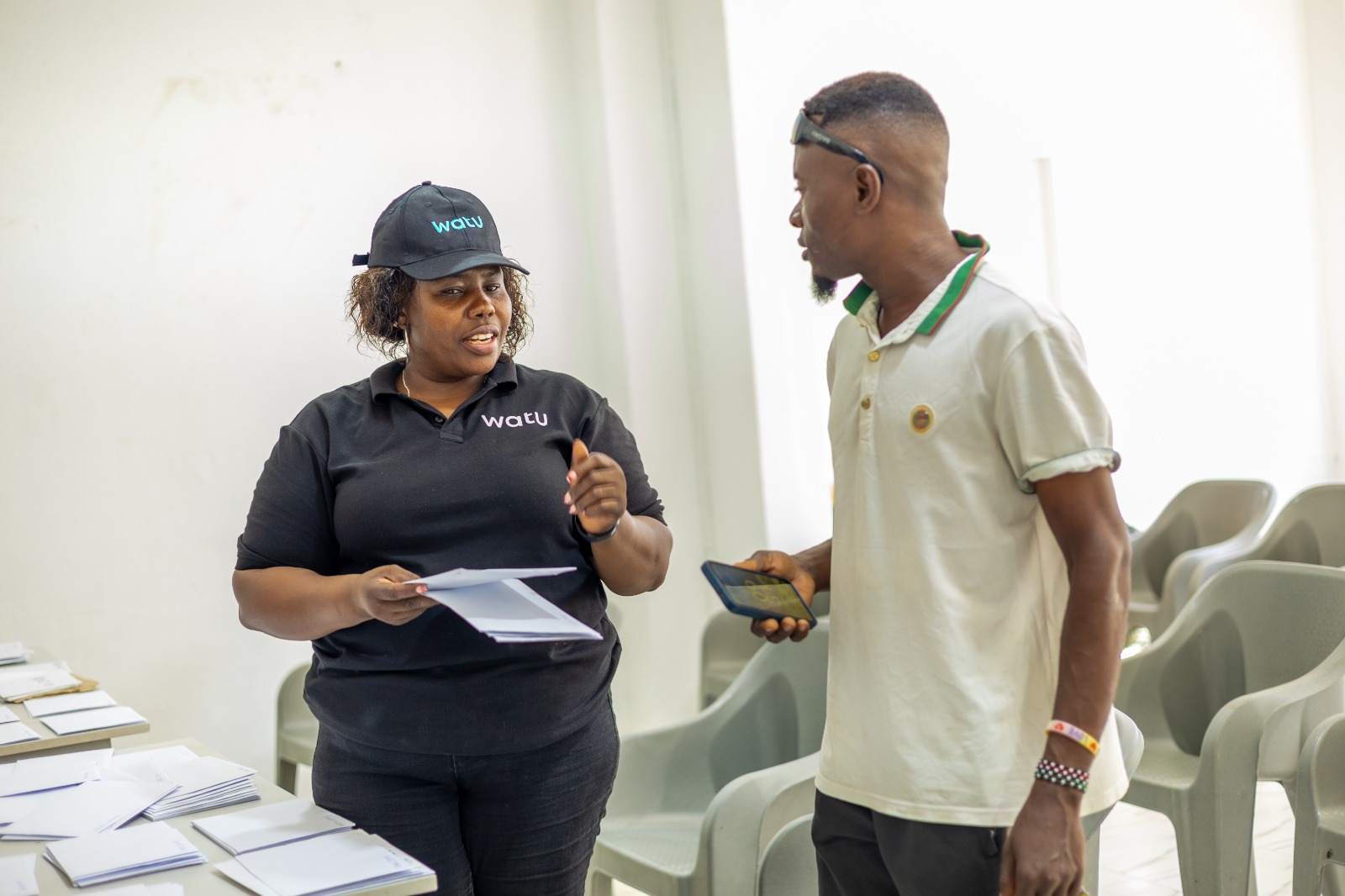 Watu Kenya Coast Regional Manager Mehetabel Mwashighadi hands over a motorcycle logbook to a customer during an asset-financing engagement in Malindi.