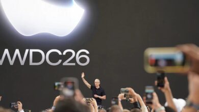 Tim Cook waves to attendees beneath a large WWDC 2026 display during Apple's annual developer conference.