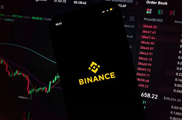 The Binance mobile app displayed against a cryptocurrency trading interface. The exchange is expanding into U.S. stock trading while preparing a tokenized equities offering for global users.