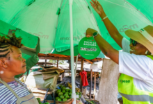 Safaricom representative helps a Kenyan woman entrepreneur set up Pochi la Biashara at a market stall.