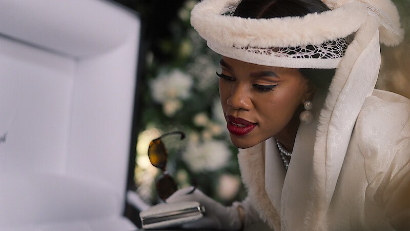 Gugu Gumede as Joyce Gomora at Jonasi Gomora's funeral in Netflix's South African drama The Polygamist, which follows a wealthy family's unraveling after years of deception and secret relationships.