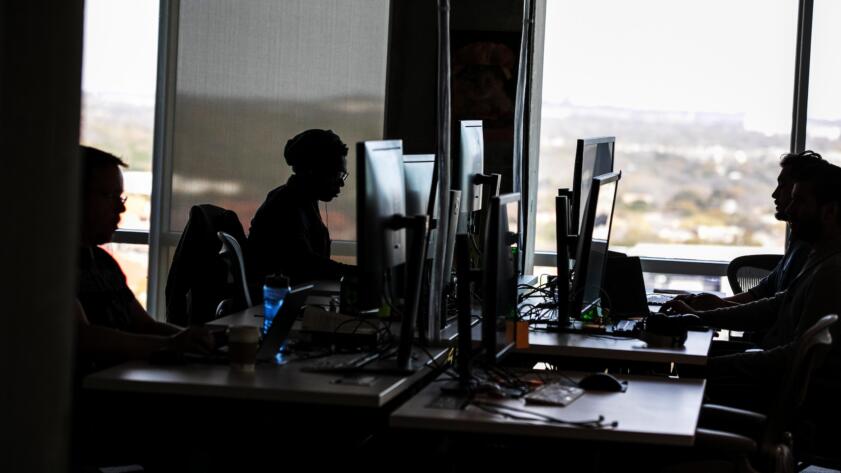 Office workers at computer stations representing AI content moderators and data annotators affected by Kenya's proposed AI worker protection policy.