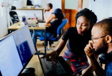 Two small business employees reviewing computer systems as part of a layered cybersecurity strategy that combines endpoint protection, multi-factor authentication and continuous monitoring.