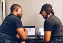 Two small business professionals reviewing cybersecurity measures on a laptop as they discuss layered security beyond traditional antivirus protection.