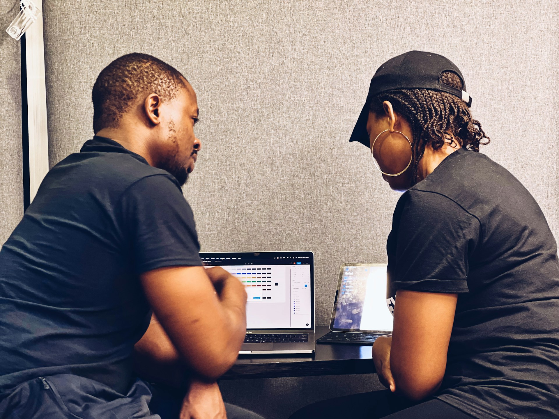 Two small business professionals reviewing cybersecurity measures on a laptop as they discuss layered security beyond traditional antivirus protection.