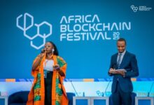 Speakers on stage at the Africa Blockchain Festival in Kigali with the event logo displayed on a large blue backdrop.