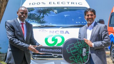 NCBA and BasiGo executives beside an electric vehicle in Kenya.
