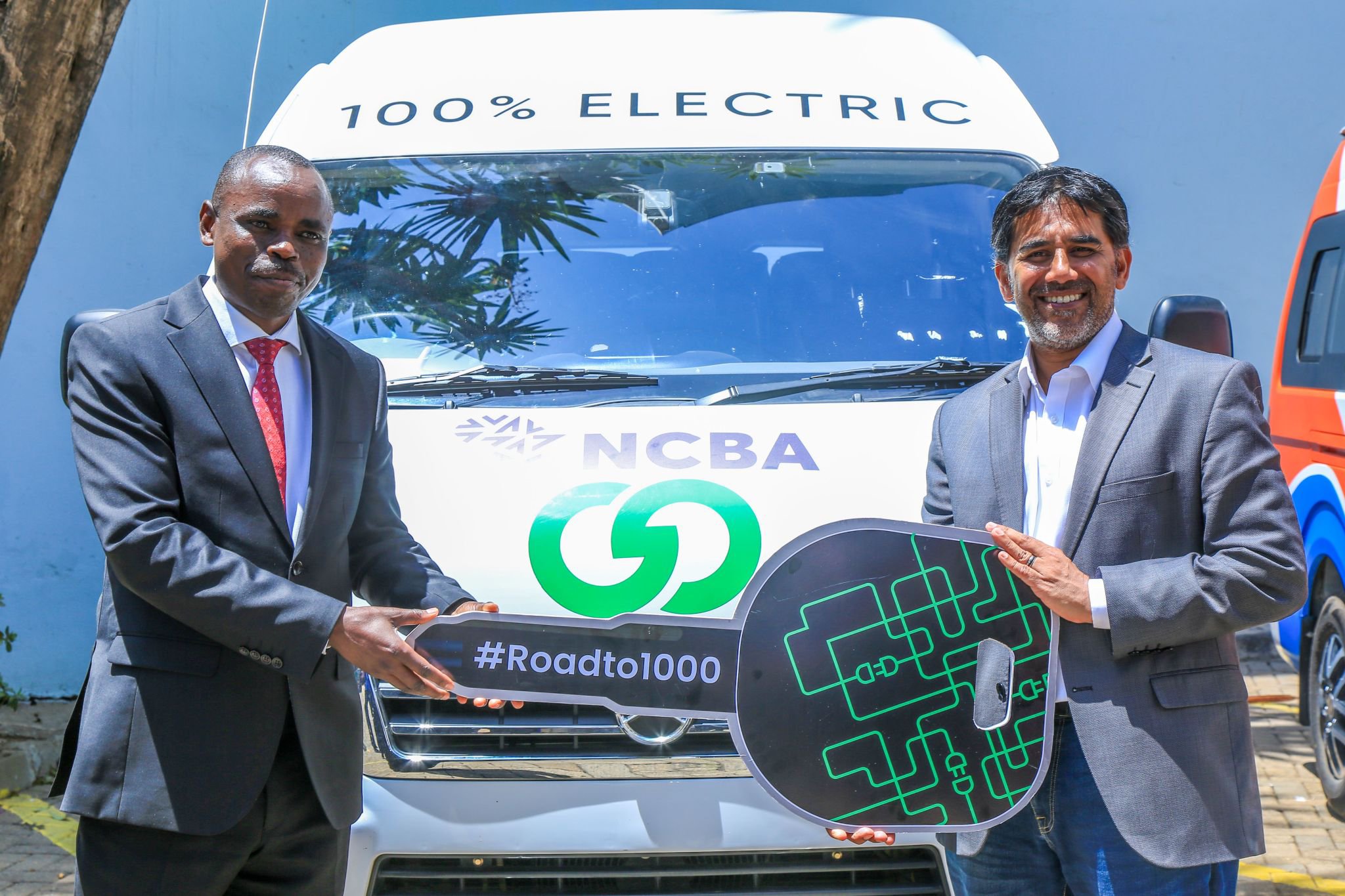 NCBA and BasiGo executives beside an electric vehicle in Kenya.