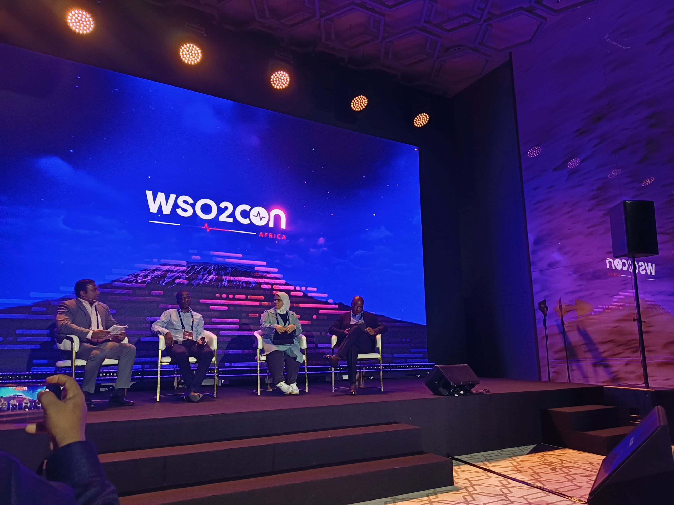 Panel discussion at WSO2Con Africa featuring Tonny Bbosa, Harrison Chapu, Hamda Al Issaei, and Dev Wijewardane discussing AI implementation in government and public services in Nairobi.