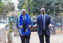 Newly appointed I&M Bank Kenya CEO Abdi Mohamed wearing a blue garland alongside Regional CEO Kihara Maina outside the bank's premises.