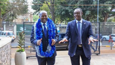 Newly appointed I&M Bank Kenya CEO Abdi Mohamed wearing a blue garland alongside Regional CEO Kihara Maina outside the bank's premises.